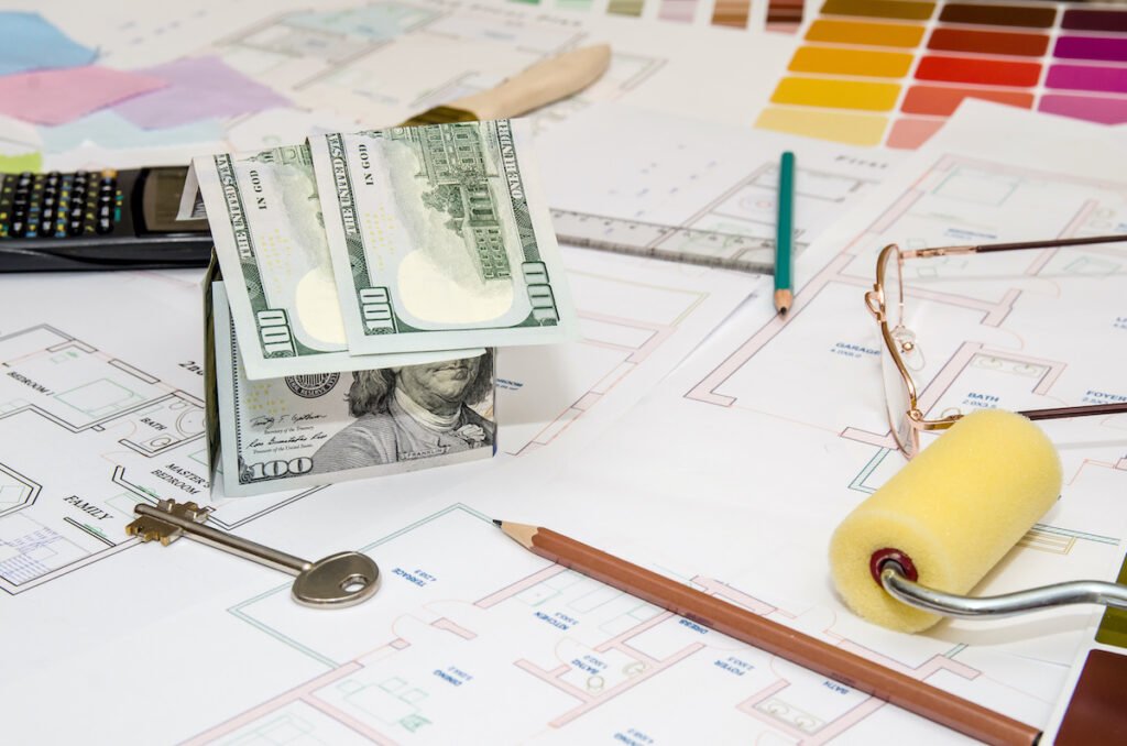 dollar banknotes as model house on a construction plan for house building for painting costs